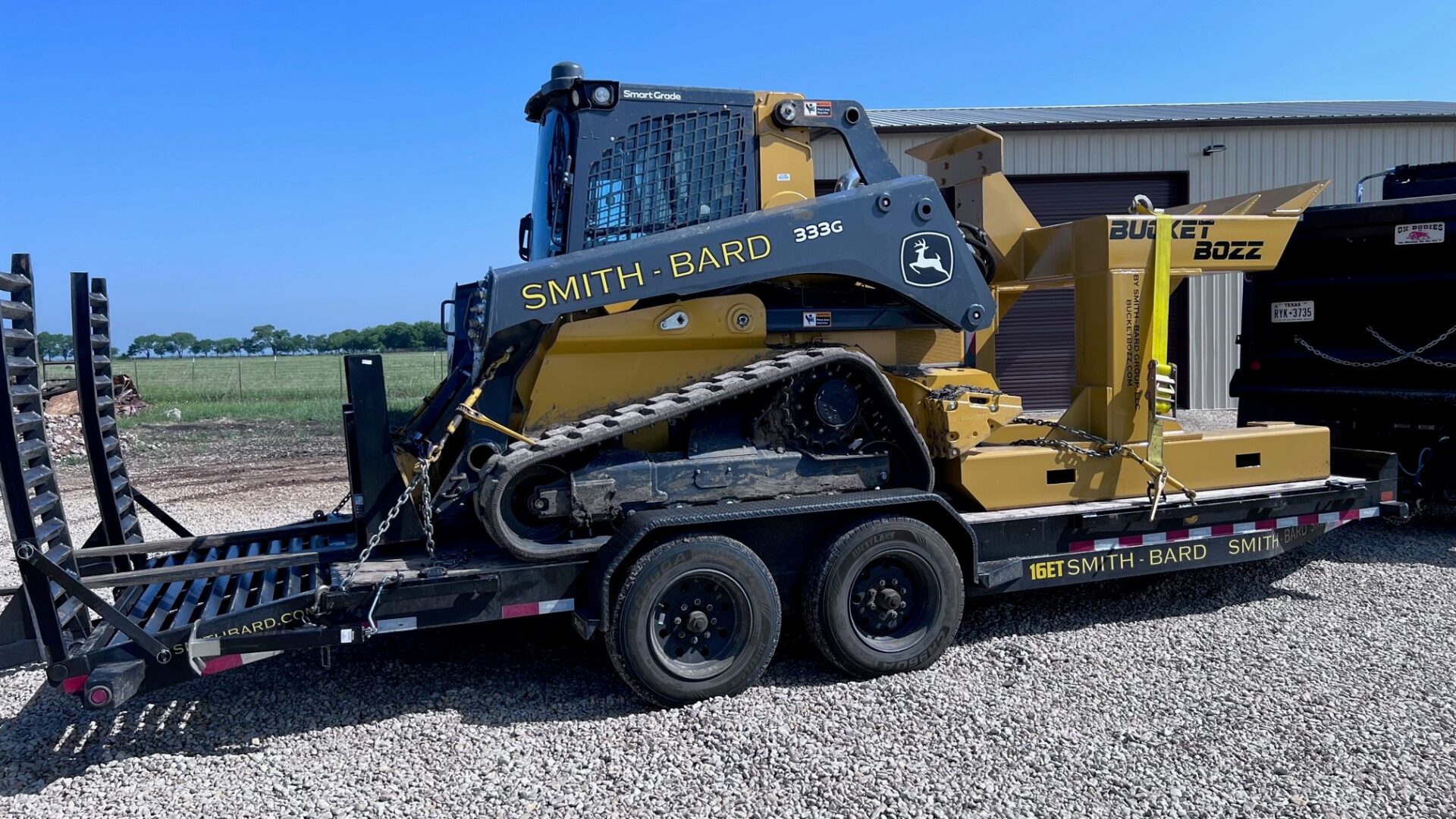 Bucket Cleaning System Loaded on a transportation trailer with a Compact Track Loader